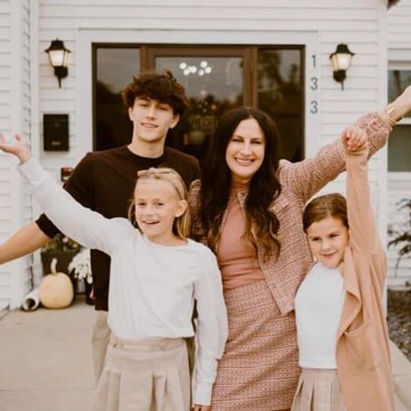 a family standing outside a white building with their arms out wide, smiling