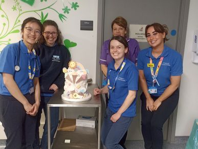 a picture of staff at the royal London hospital posing with their razzmatazz cake won in a rafffle