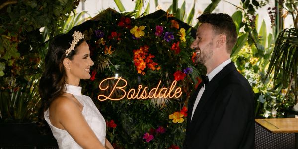 Bride and groom holding hands under floral arch at Boisdale.