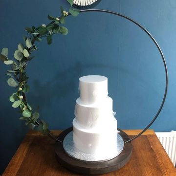 80cm hoop cake stand in 10mm solid steel and 45cm round rustic base on a table with foliage