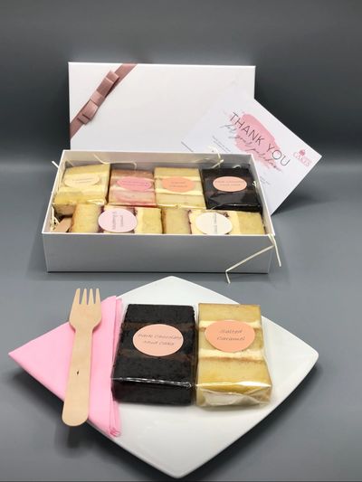 Luxury Treat Box decorated with pibnk ribbon filled with 6 cake slices, and 2 cake slices on a plate