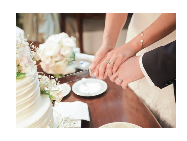 Couples' hand cutting wedding cake together