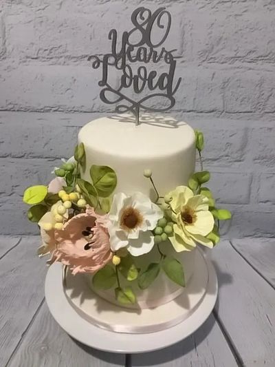 Two-tier 80th birthday cake with handmade sugar flowers and silver number topper