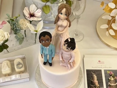 Handmade sugar pageboy, bridesmaid and flower girl on top of a pink cake on a table