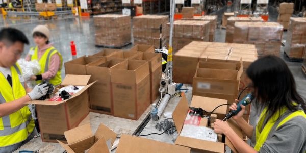 Workers packing products into boxes in a warehouse.
