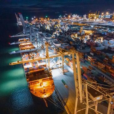A bustling container port at night illuminated with lights.