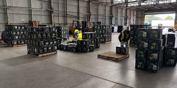 Workers organizing and stacking boxes inside a large warehouse.
