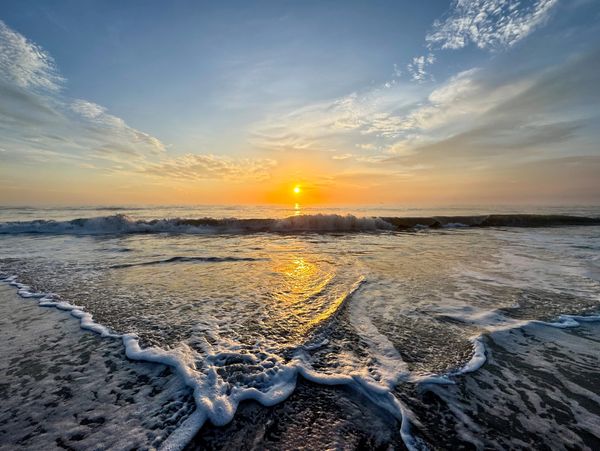 Gentle Waves
Golden hues of a sunset reflect on the gentle waves as they kiss the shoreline. Wispy c