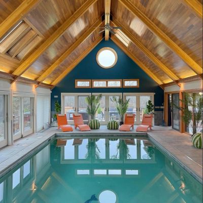 Indoor pool with wooden vaulted ceiling and orange lounge chairs.