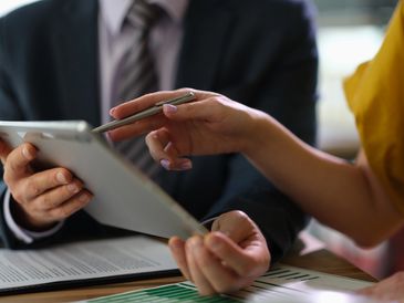 Two business partners are discussing information on tablet computer. Collaborate and discuss project