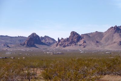 Desert landscape with distant rocky mountains under blue sky.