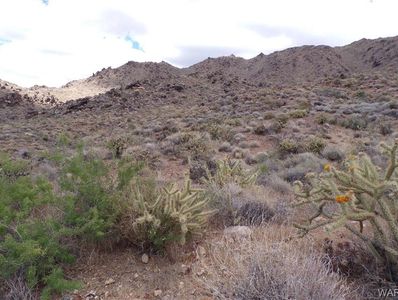 Desert landscape with cacti and rocky hills under a partly cloudy sky.