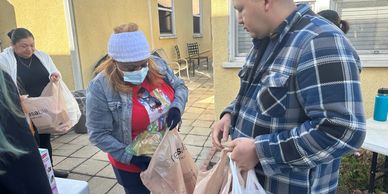 volunteer handing groceries to a man needing food