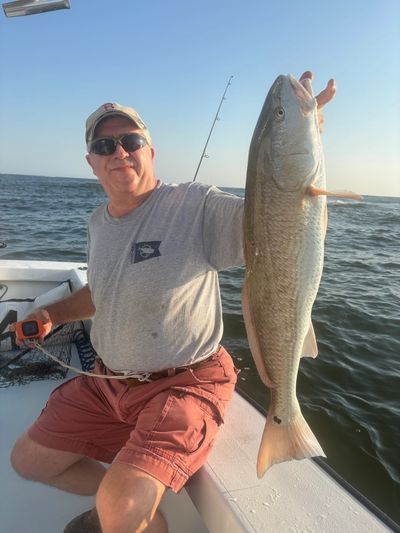 Man proudly holding a large fish on a boat.