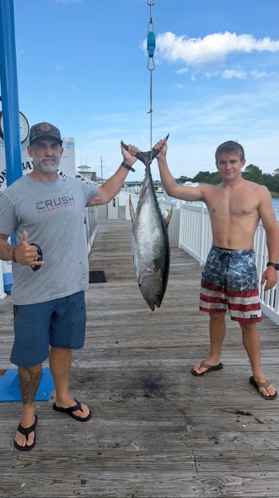 Two men holding a large fish at a dock.