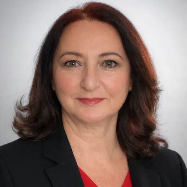 Professional woman with shoulder-length brown hair, wearing a black blazer and red top.