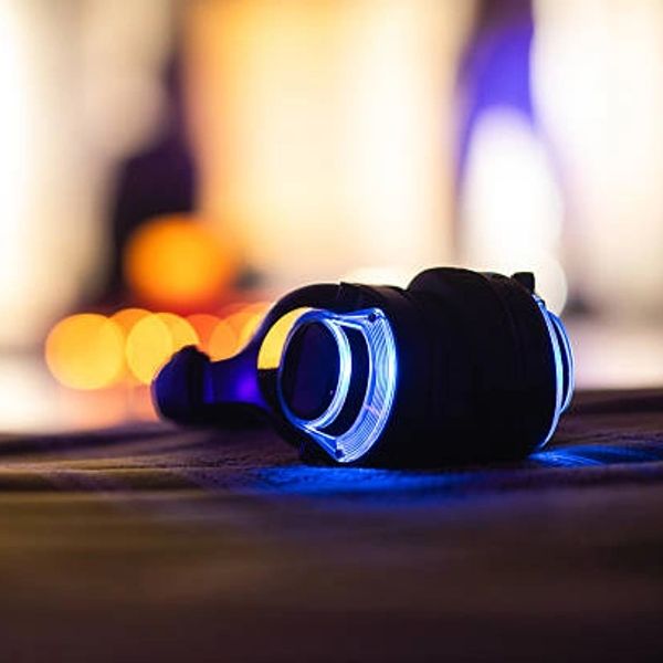Black headphones with blue neon lights resting on a surface.