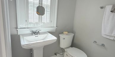 A clean, simple bathroom with a pedestal sink and toilet.