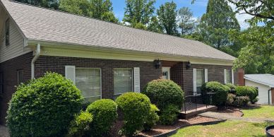 A single-story brick house with bushes in front.