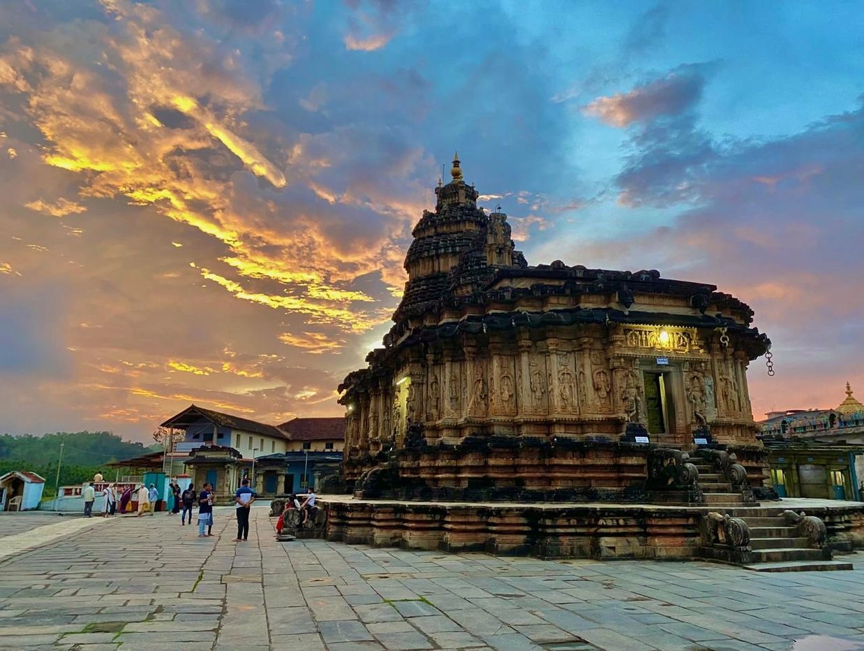 Ancient stone temple with intricate carvings under a dramatic sunset sky.