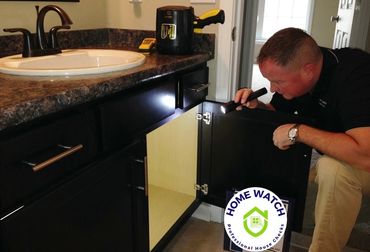 Dan Powell is checking the plumbing of a bathroom sink with a flashlight.