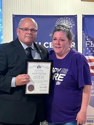 Man in suit presents certificate to woman in purple shirt at event.