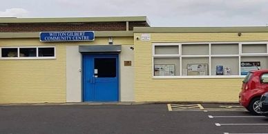 Wilton Gilbert Community Centre building with a blue door and beige walls.