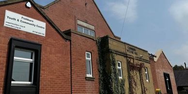 Community center building with signs on red brick walls.