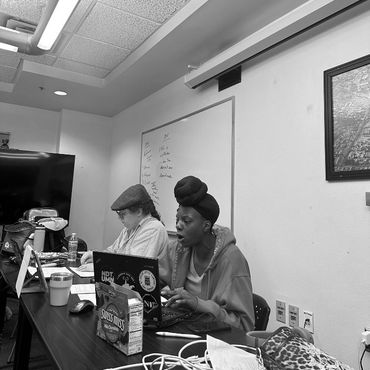 Two people working on laptops in a conference room with a whiteboard.