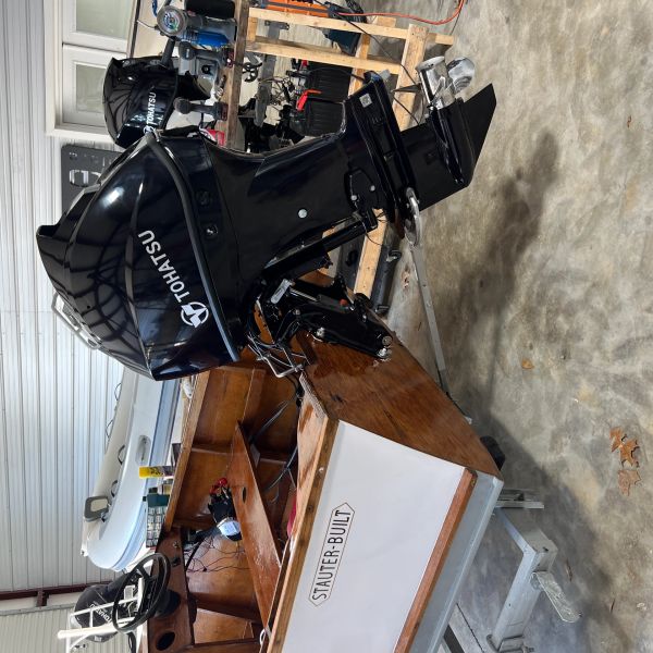 Wooden boat with Tohatsu outboard motor in a workshop.
