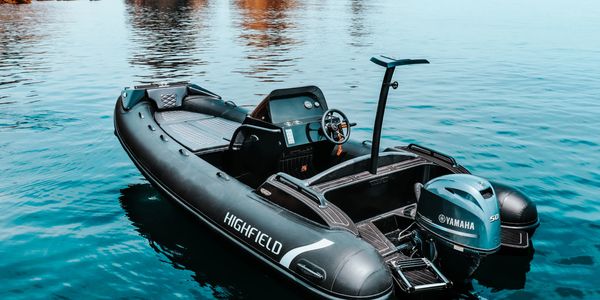 Black Highfield inflatable boat with Yamaha motor on calm water.