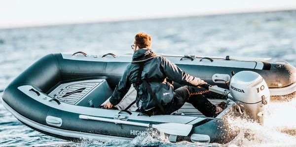 Person steering an inflatable boat on water.