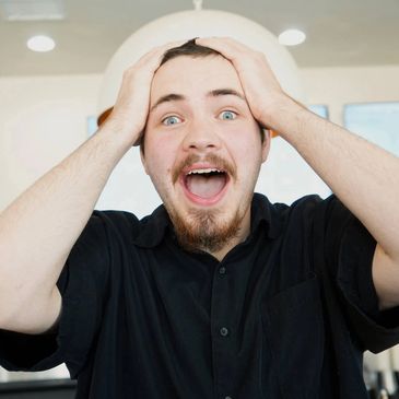 Excited young man holding his head in surprise and joy.