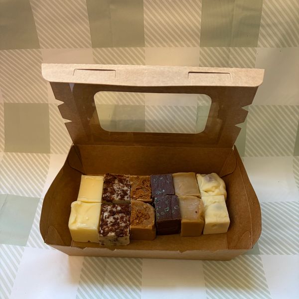 Assorted fudge pieces neatly arranged in a brown cardboard box.
