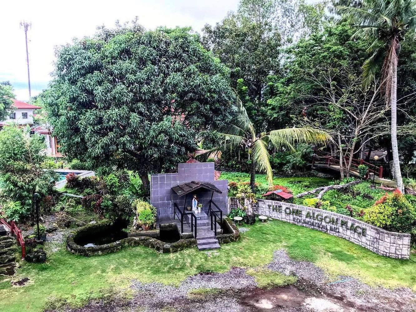 A lush garden area with a statue, large trees, and a sign reading 'THE ONE ALGON PLACE'.