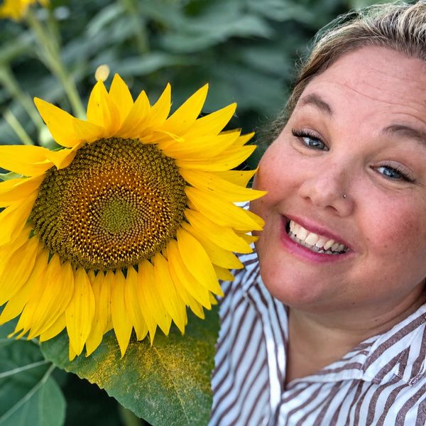 Smiling woman posing with a bright sunflower.