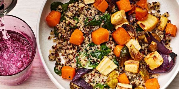 Quinoa salad with roasted vegetables and a purple drink being poured.