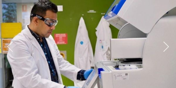 Scientist operating lab equipment wearing protective gear.