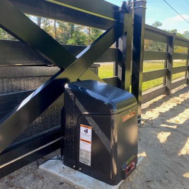 Automatic gate opener installed at a black wooden gate.