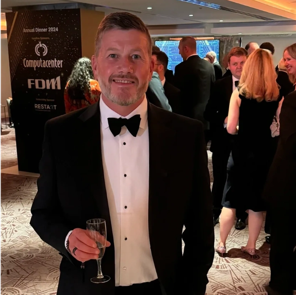 Man in tuxedo holding a glass at a formal event.