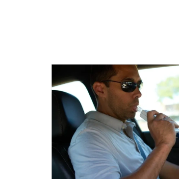 Man using breathalyzer inside a car.