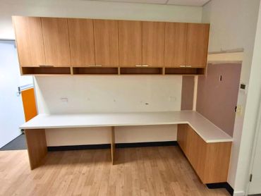 Empty office workspace with wooden cabinets and white countertops.