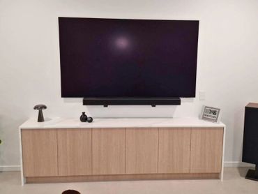 Modern living room setup with a large flat-screen TV mounted above a wooden cabinet.