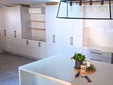 Modern kitchen with white cabinetry and a central island decorated with plants and candles.
