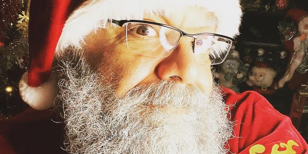 A man dressed as Santa Claus with glasses and a detailed beard.