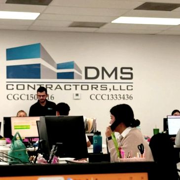 Office scene at DMS Contractors with employees working at desks.