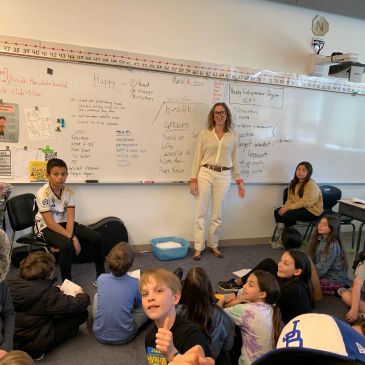 Teacher and students in a lively classroom during a group activity.