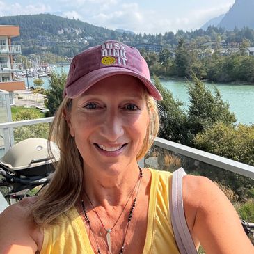Woman smiling with scenic mountain and lake background.