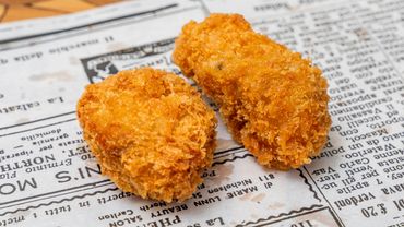 Two golden, crispy fried nuggets on newspaper.