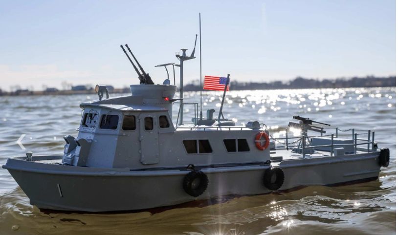 Model of a military patrol boat on water with an American flag.
